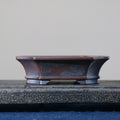 Flared rim and decorative feet of dark-brown mokko pot