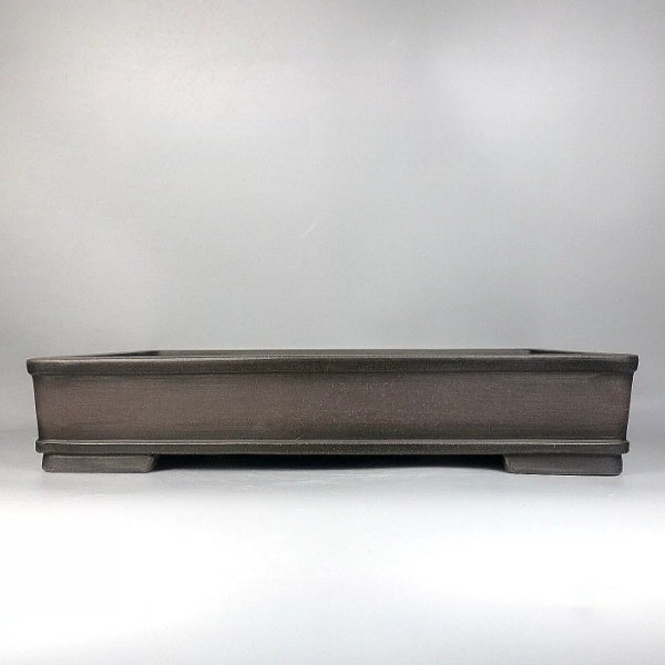 Front view of a long dark brown rectangular bonsai pot with raised rim and short feet