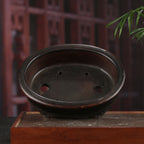 Dark-brown oval pot interior with drainage openings