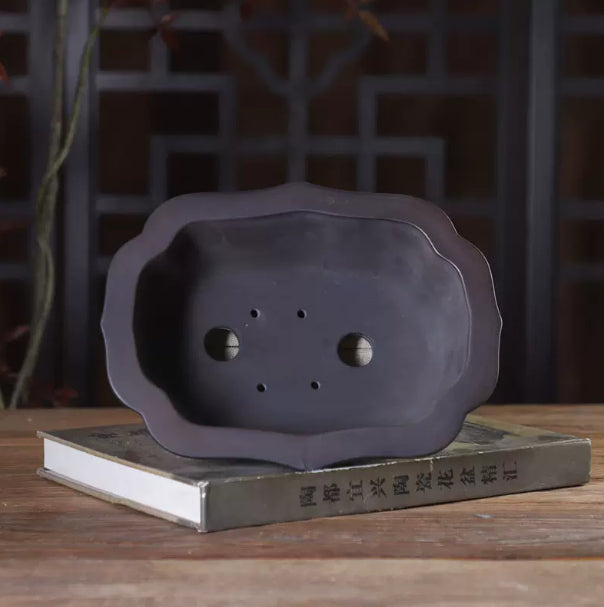 Interior of the dark lobed pot showing two drainage holes and four smaller openings