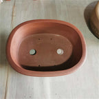 Top view of brown oval pot showing two large openings and small holes