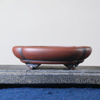 Red-brown lobed bonsai pot with dark accents and curled feet