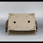 Underside of the taupe pot with decorative feet and two drainage holes