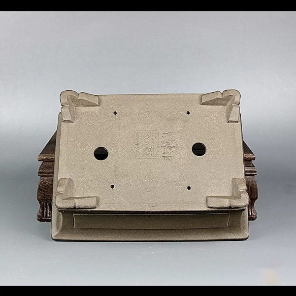 Underside of the taupe pot with decorative feet and two drainage holes
