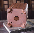 Base of the tall square pot showing one central drainage hole, four smaller openings and raised feet