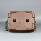 Underside of the brown rectangular pot showing two drainage holes and impressed marks