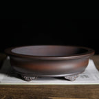 Front view of the brown oval pot with decorative feet