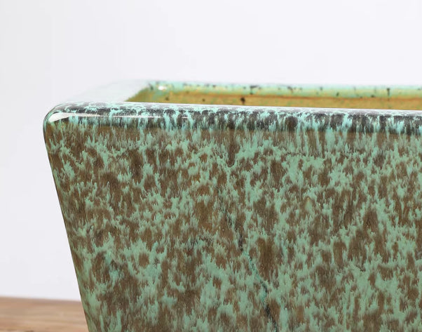 Close-up of green and brown speckled glaze at pot rim and corner