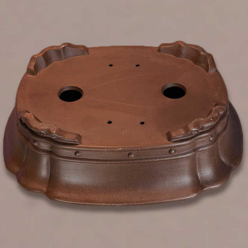 Underside of brown lobed pot showing two large openings and corner feet
