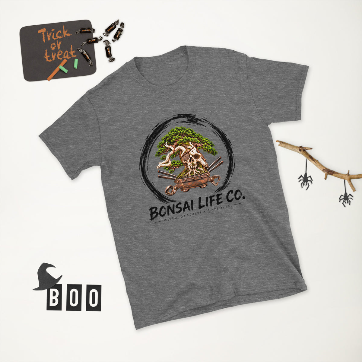 heathered dark gray T-shirt with green bonsai and pirate skull graphic inside a black circle with Bonsai Life Co. lettering, white Halloween flat lay