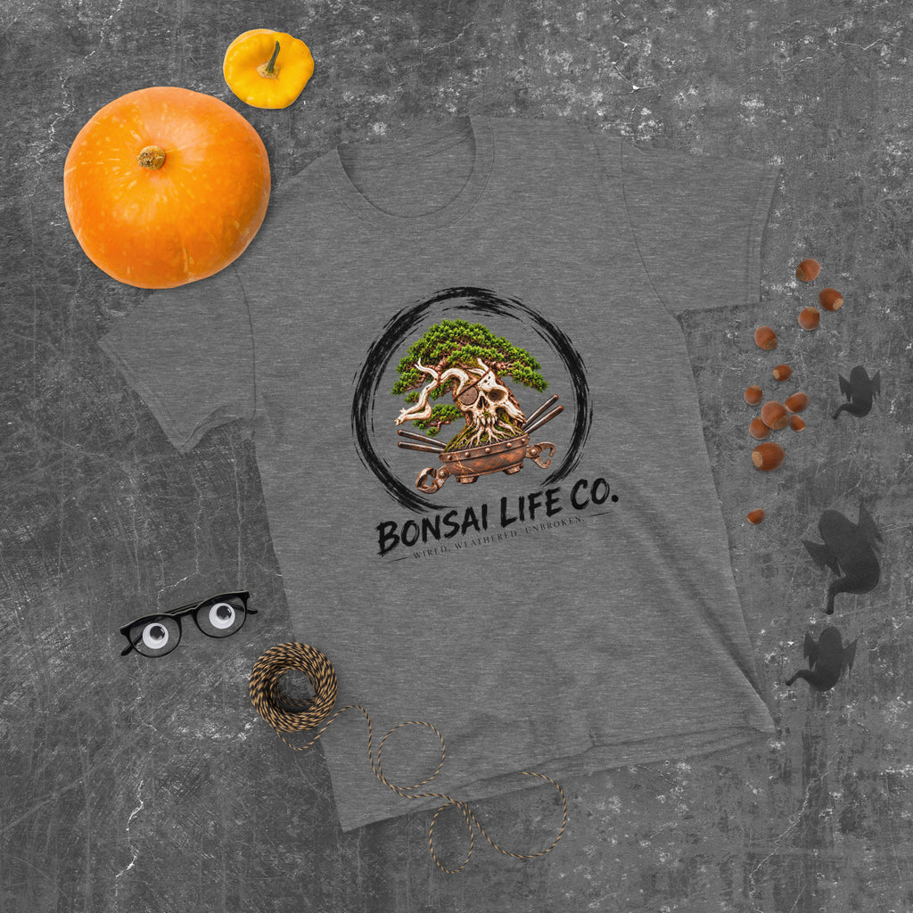 heathered dark gray T-shirt with green bonsai and pirate skull graphic inside a black circle with Bonsai Life Co. lettering, gray flat lay with pumpkins