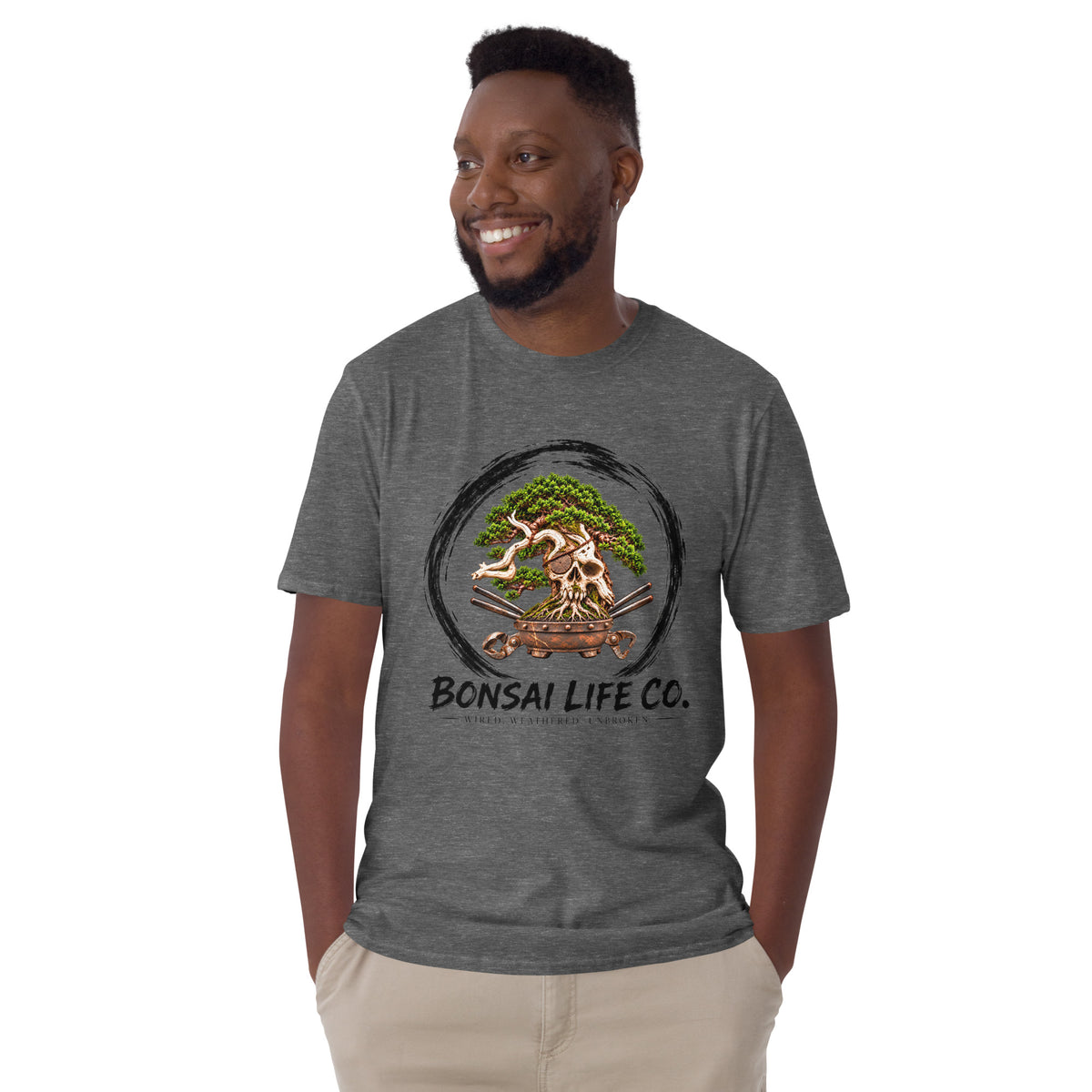 Model wearing heathered dark gray T-shirt with green bonsai and pirate skull graphic inside a black circle with Bonsai Life Co. lettering, front view
