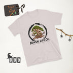 pale gray T-shirt with green bonsai and pirate skull graphic inside a black circle with Bonsai Life Co. lettering, white Halloween flat lay