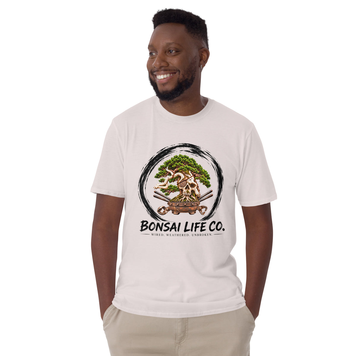 Model wearing pale gray T-shirt with green bonsai and pirate skull graphic inside a black circle with Bonsai Life Co. lettering, front view