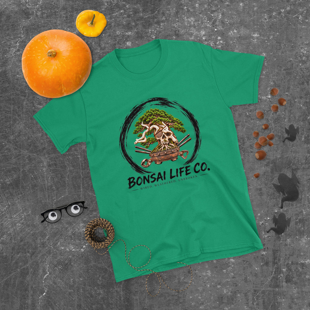bright green T-shirt with green bonsai and pirate skull graphic inside a black circle with Bonsai Life Co. lettering, gray flat lay with pumpkins