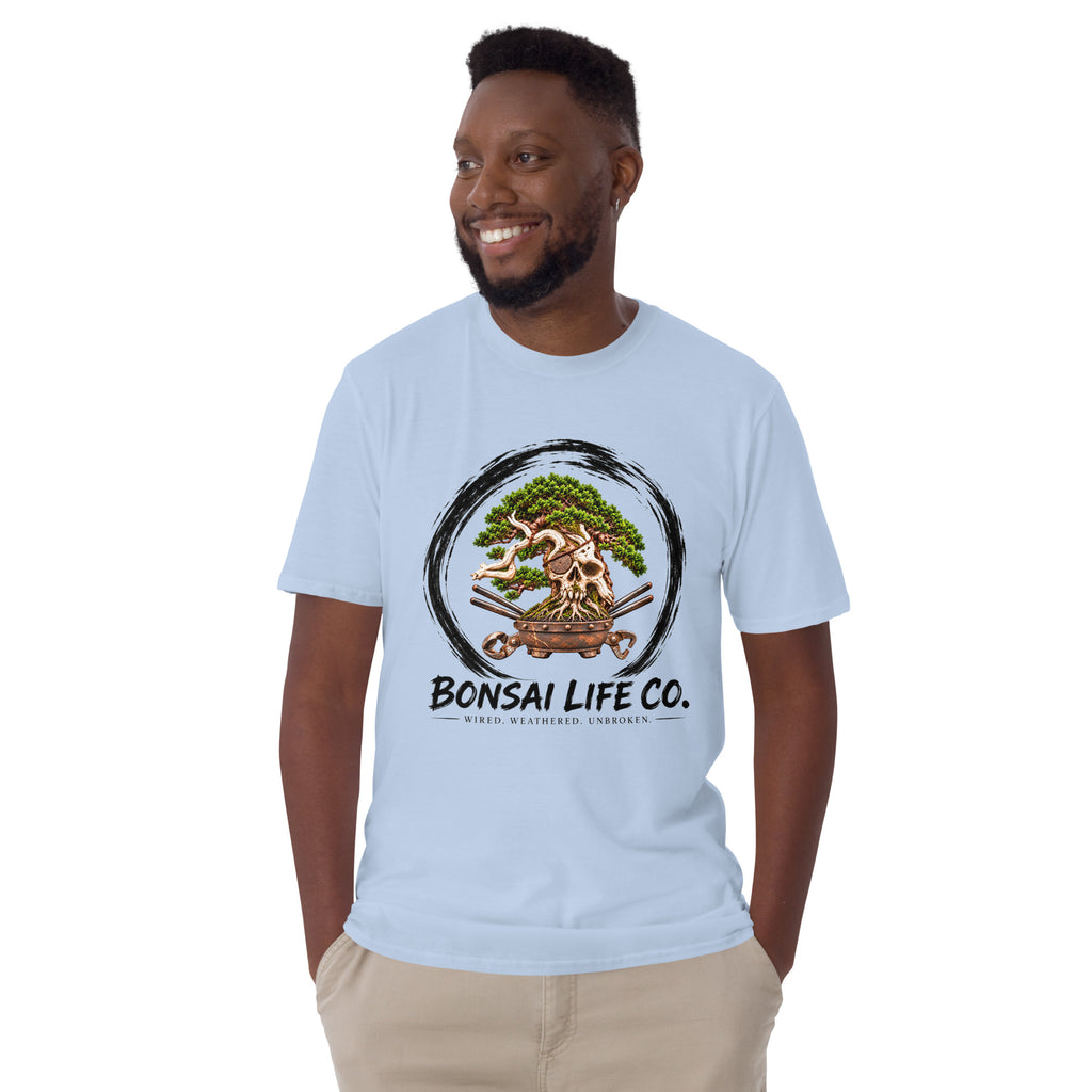 Model wearing light blue T-shirt with green bonsai and pirate skull graphic inside a black circle with Bonsai Life Co. lettering, front view
