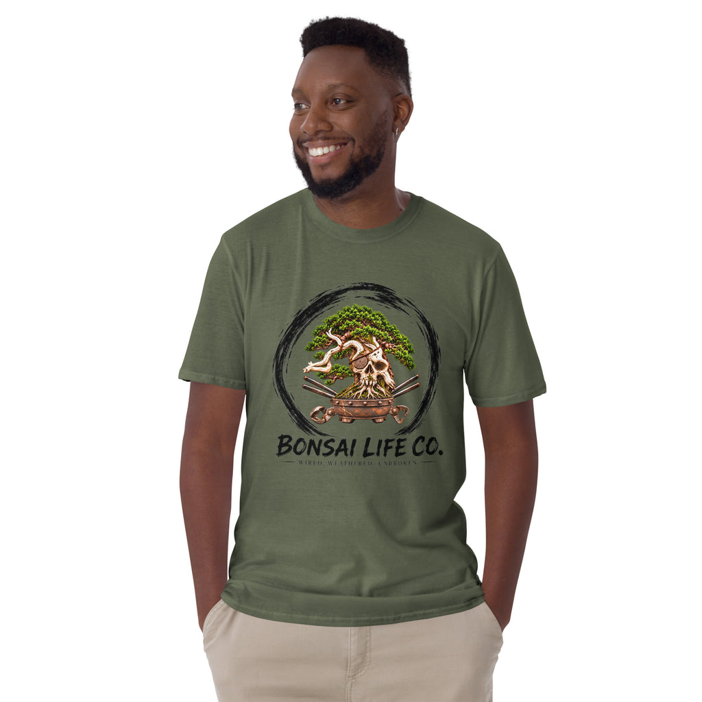 Model wearing muted olive green T-shirt with green bonsai and pirate skull graphic inside a black circle with Bonsai Life Co. lettering, front view
