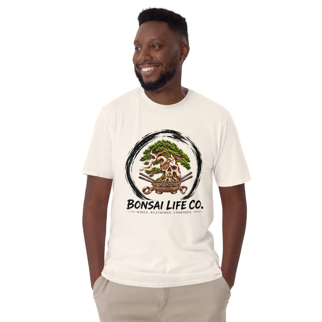 Model wearing cream T-shirt with green bonsai and pirate skull graphic inside a black circle with Bonsai Life Co. lettering, front view