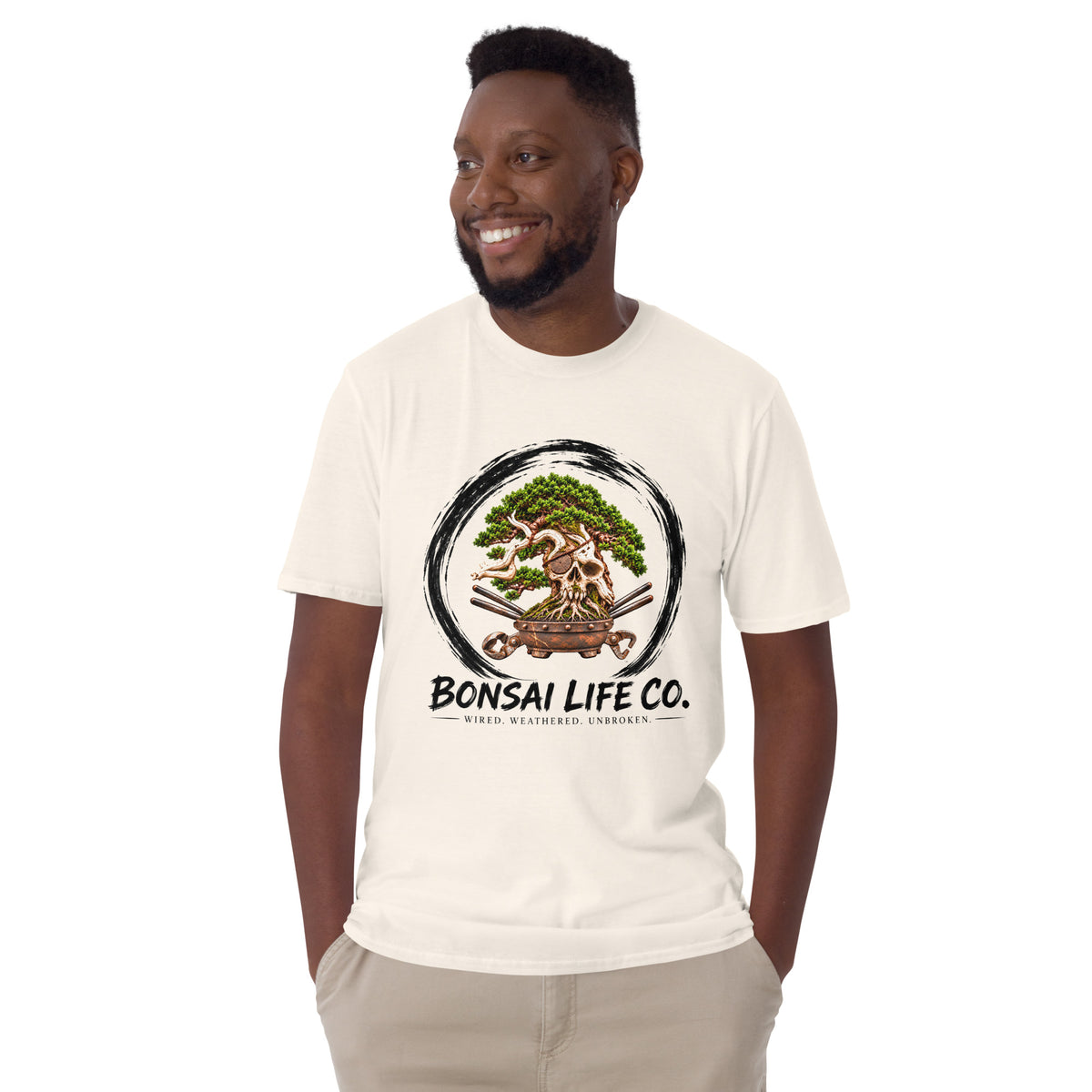 Model wearing cream T-shirt with green bonsai and pirate skull graphic inside a black circle with Bonsai Life Co. lettering, front view