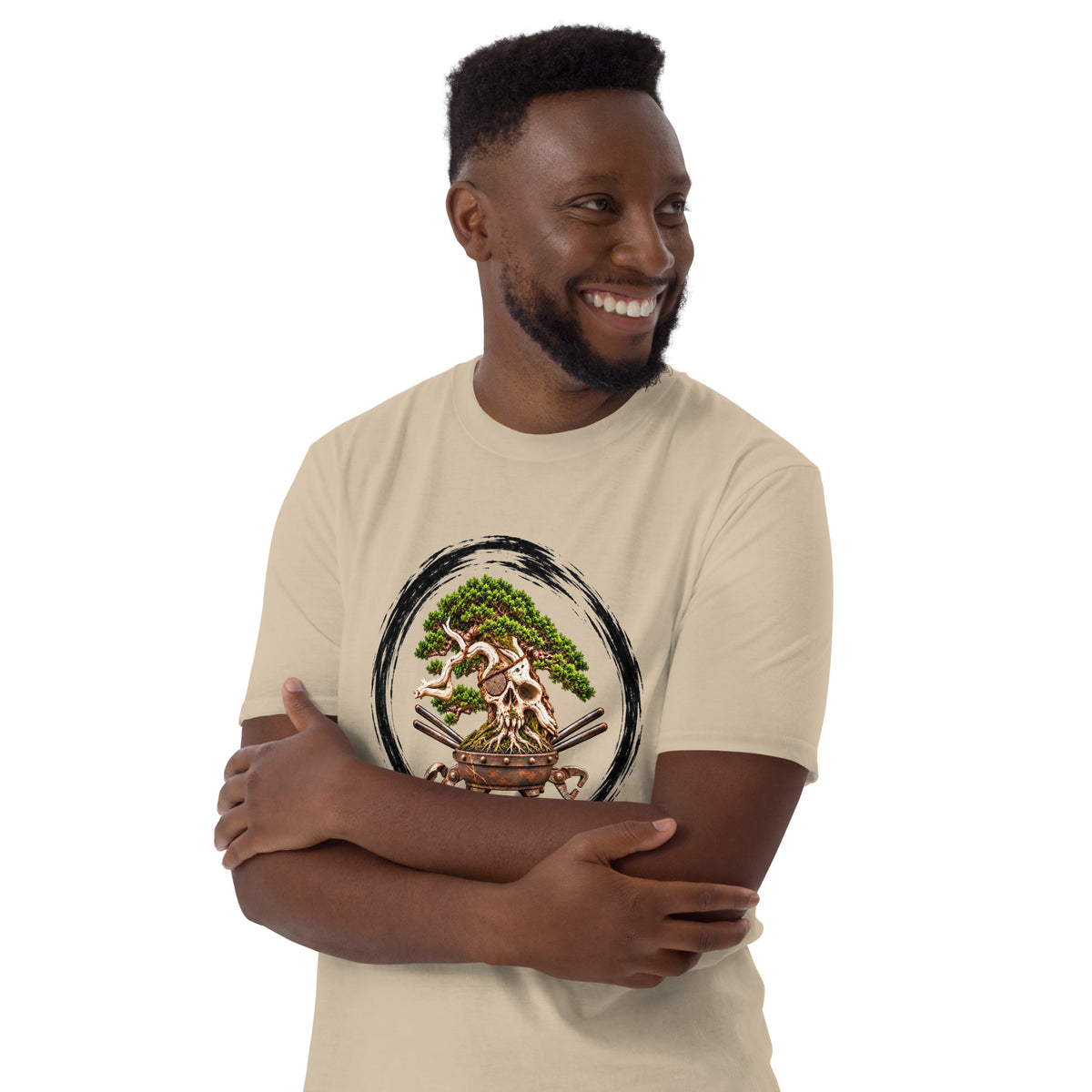 Model wearing sand beige T-shirt with green bonsai and pirate skull graphic inside a black circle with Bonsai Life Co. lettering, arms-crossed close view