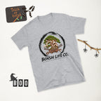 heathered light gray T-shirt with green bonsai and pirate skull graphic inside a black circle with Bonsai Life Co. lettering, white Halloween flat lay