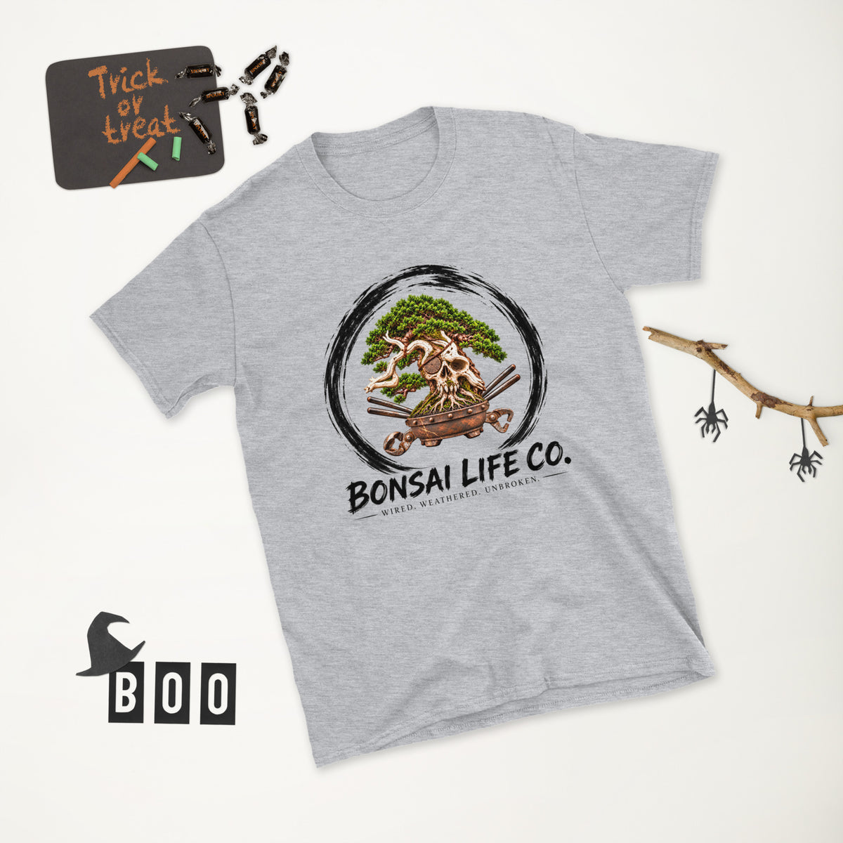 heathered light gray T-shirt with green bonsai and pirate skull graphic inside a black circle with Bonsai Life Co. lettering, white Halloween flat lay