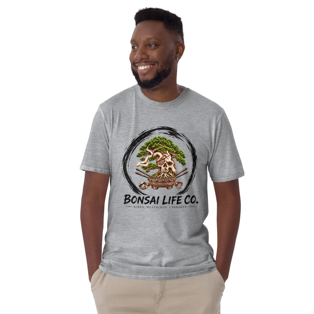 Model wearing heathered light gray T-shirt with green bonsai and pirate skull graphic inside a black circle with Bonsai Life Co. lettering, front view