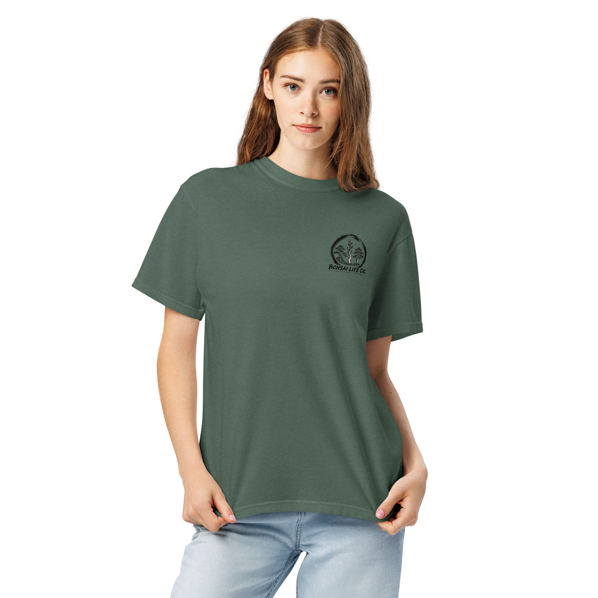 Model wearing muted blue-green T-shirt with small circular Three Trees chest logo, closer front view