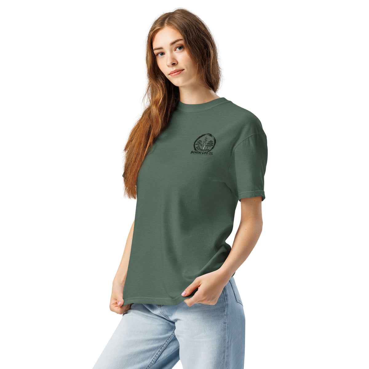 Model wearing muted blue-green T-shirt with small circular Three Trees chest logo, angled front view