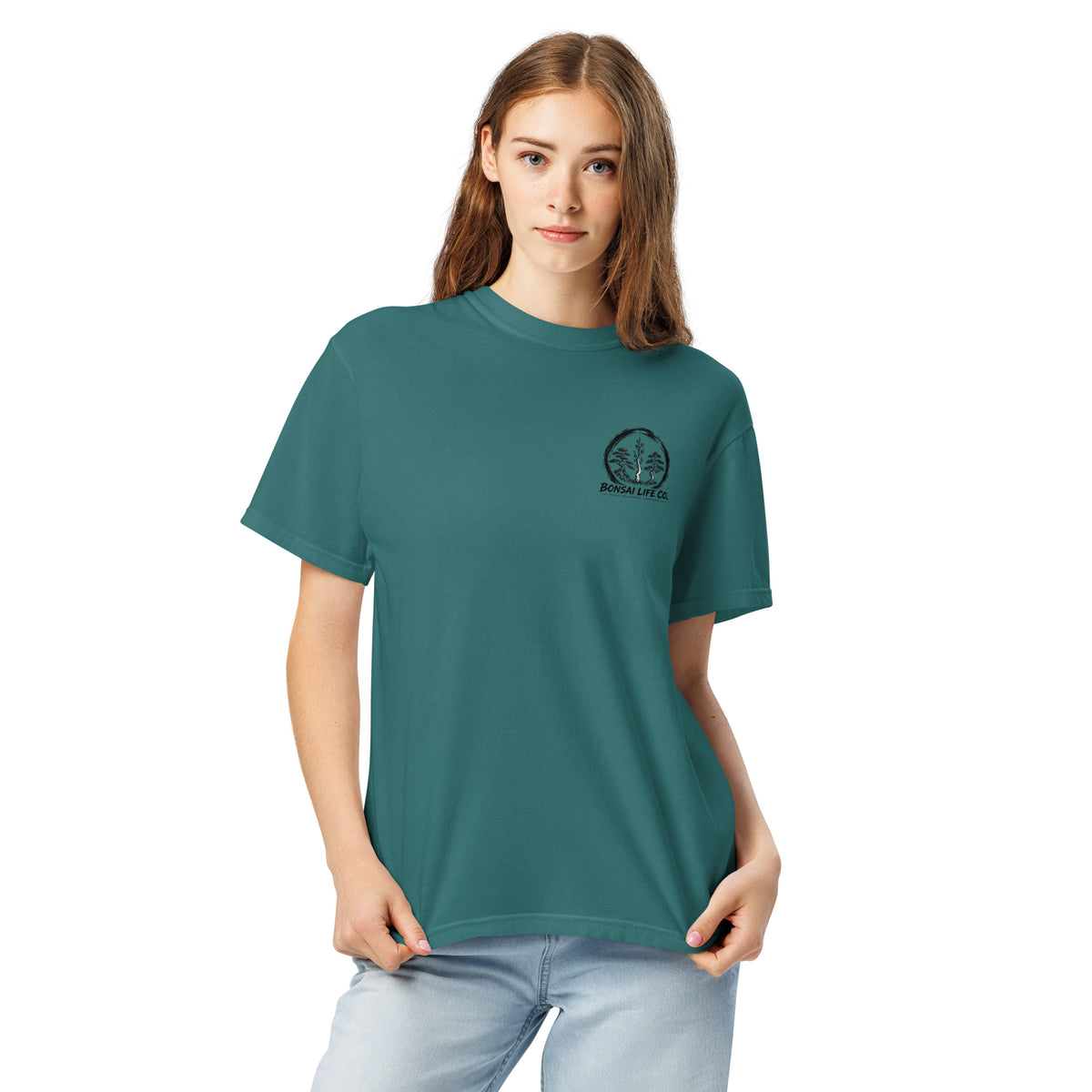Model wearing teal green T-shirt with small circular Three Trees chest logo, closer front view