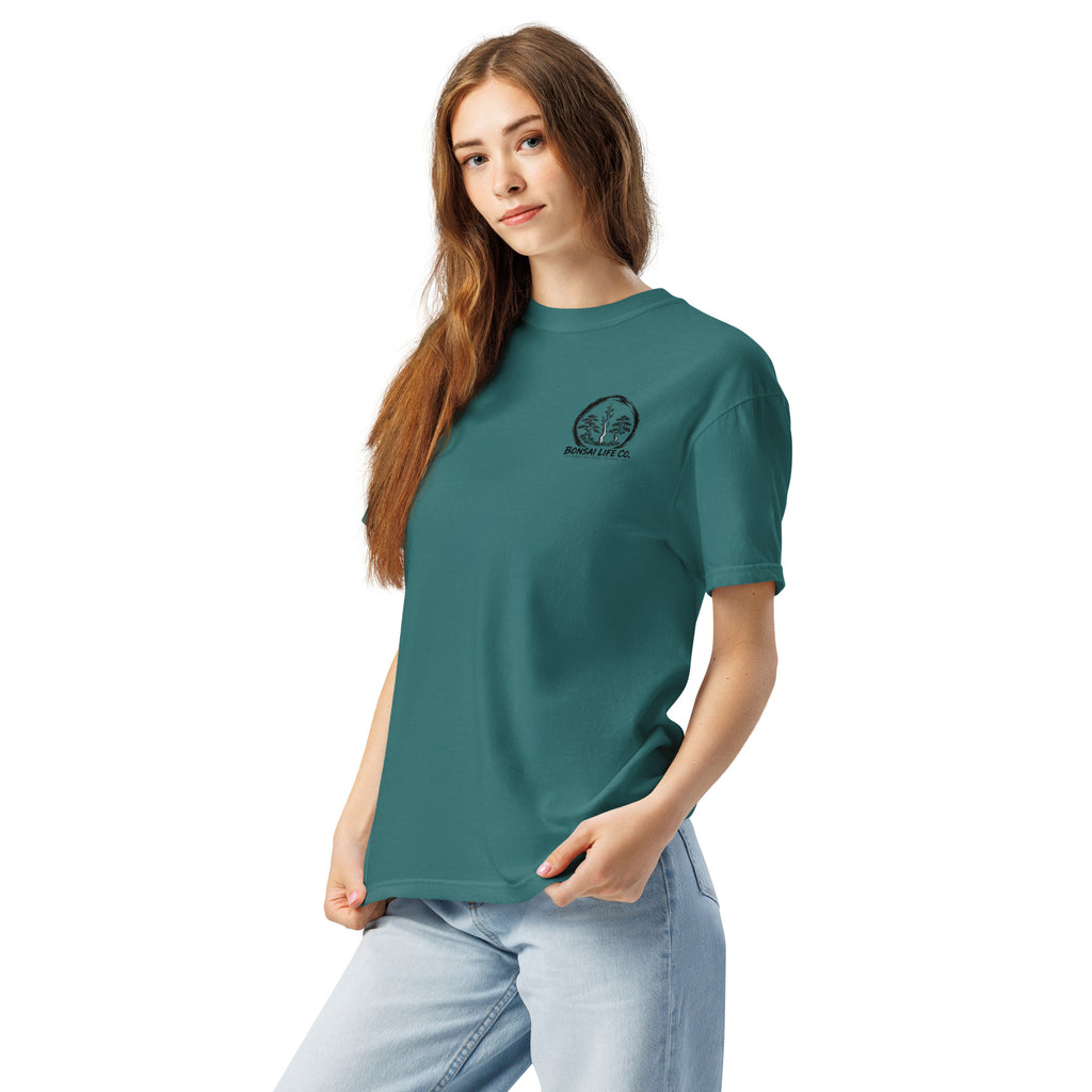 Model wearing teal green T-shirt with small circular Three Trees chest logo, angled front view