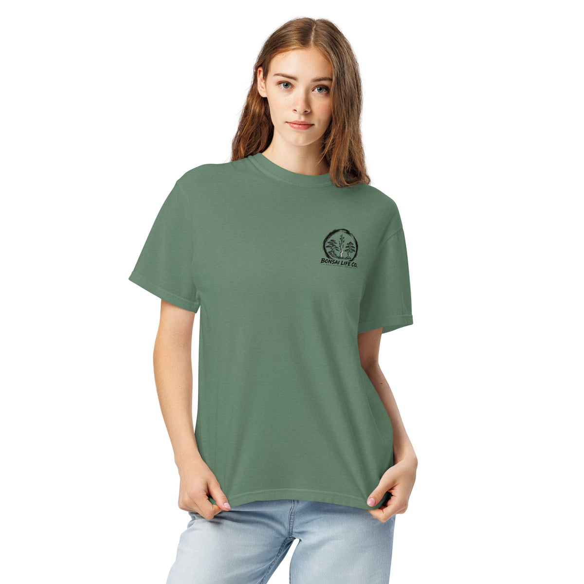 Model wearing sage green T-shirt with small circular Three Trees chest logo, closer front view
