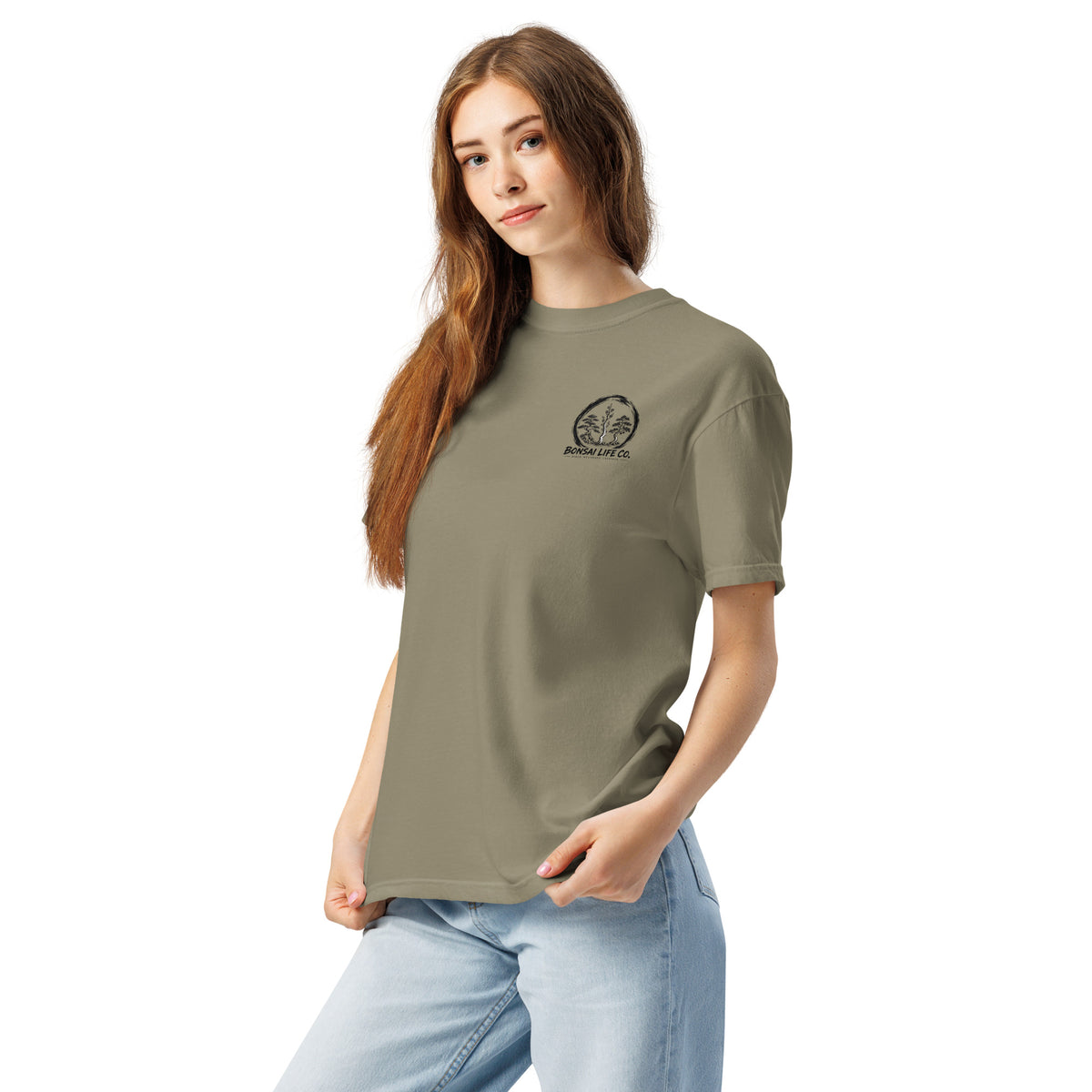 Model wearing gray-beige T-shirt with small circular Three Trees chest logo, angled front view