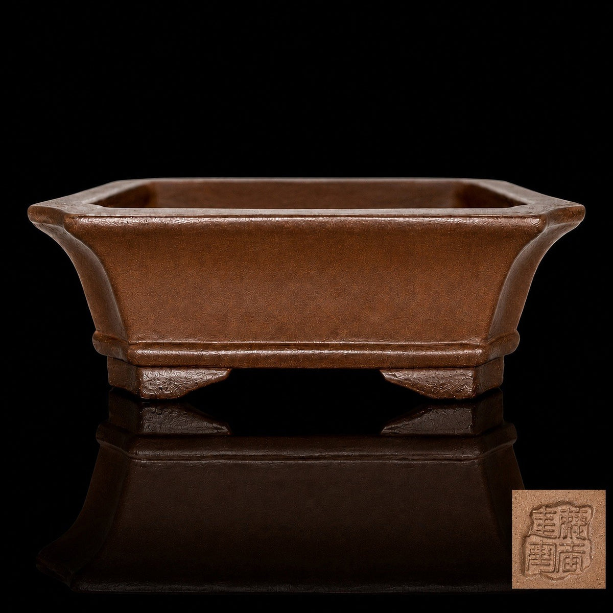 Brown rectangular bonsai pot on a reflective black surface, with an inset showing its impressed seal