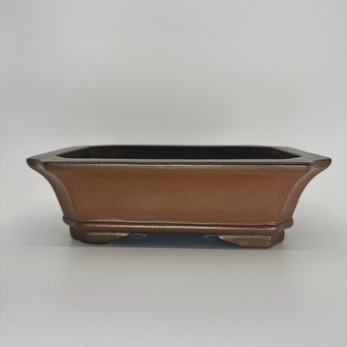 Brown rectangular bonsai pot with flared sides, clipped corners and low sculpted feet