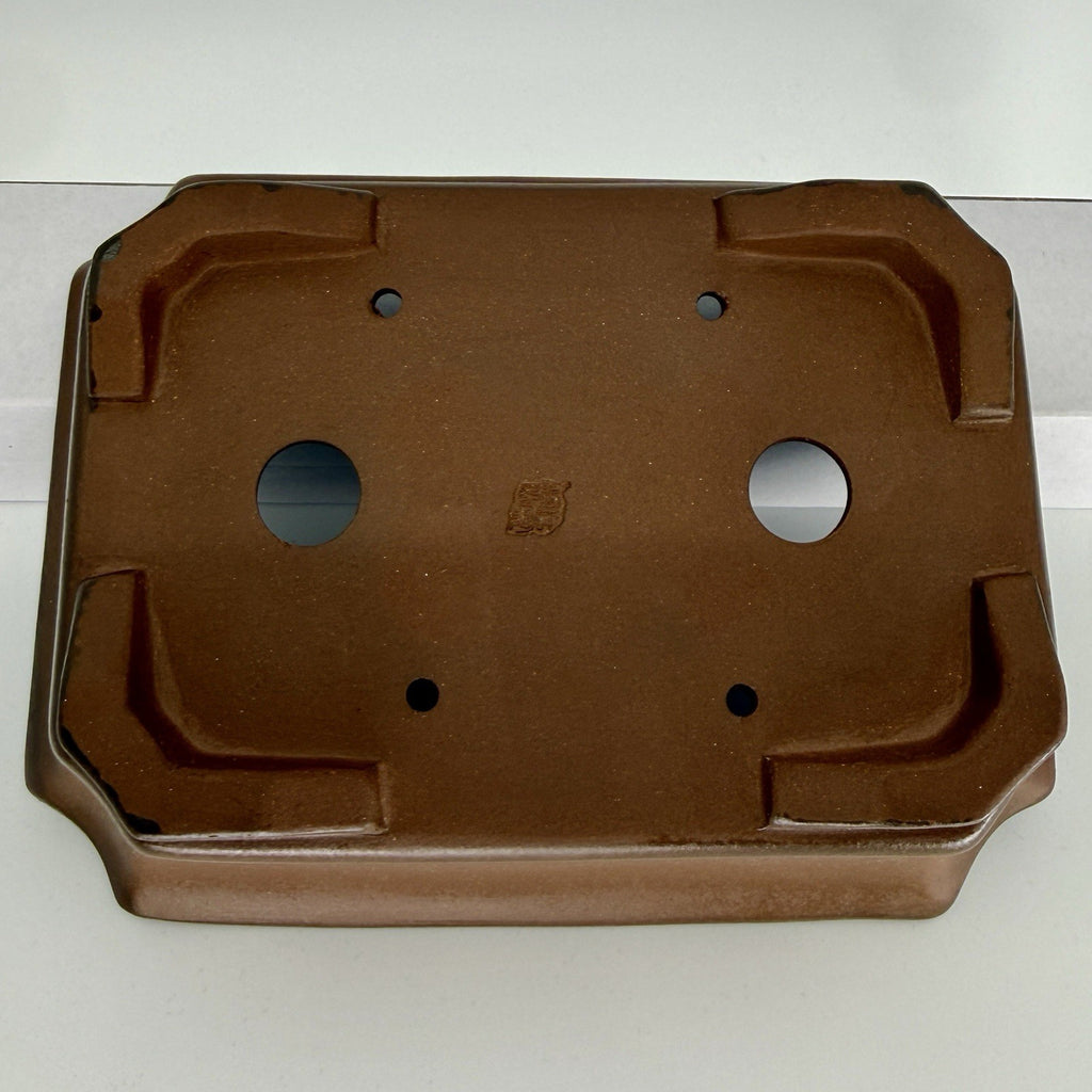 Close underside view of the brown pot with two drainage holes and four smaller tie-down openings