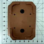Brown rectangular pot base on a gridded measuring mat, showing drainage holes and corner feet