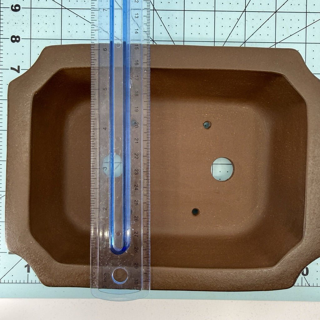 Ruler spanning the width of the brown rectangular pot's interior opening